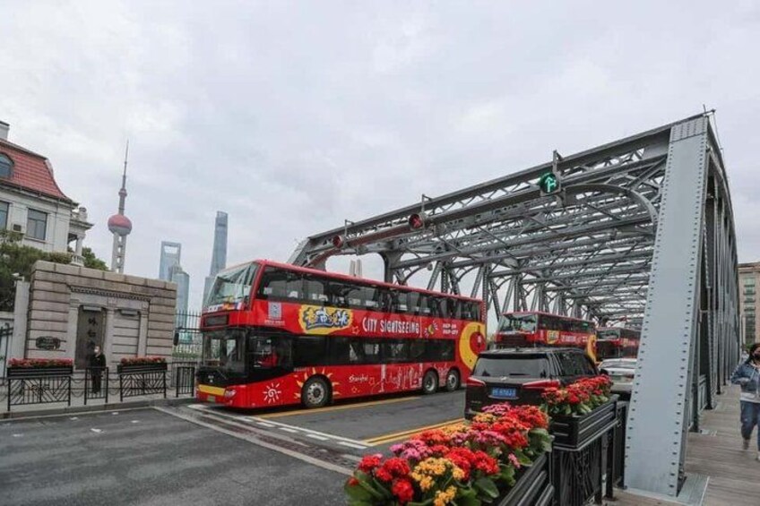A red double-decker bus on a bridge with a cityscape in the background. 4