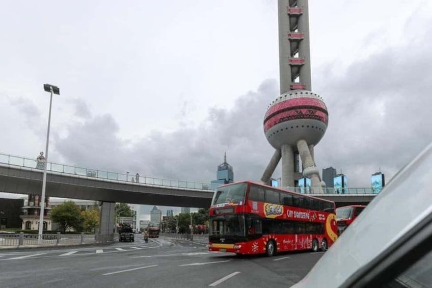 A red double-decker bus on a city street with a large tower in the background. 5