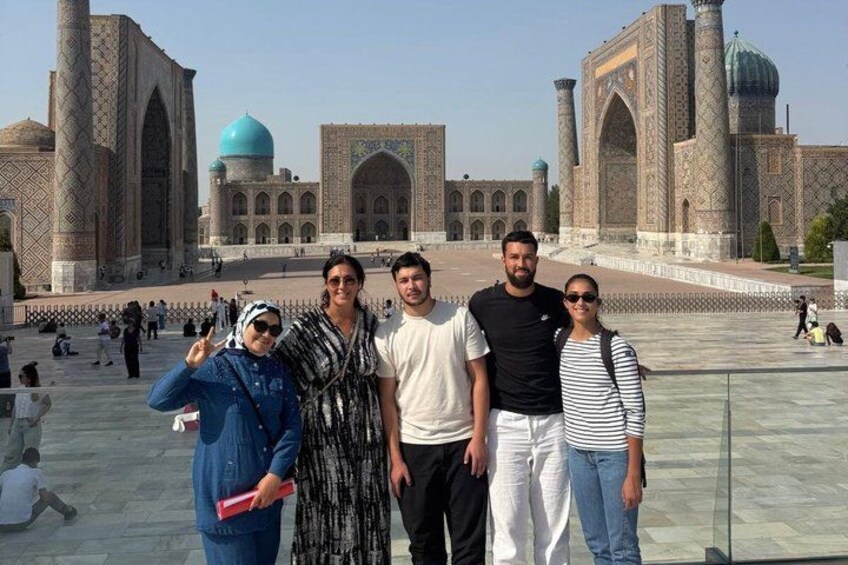 A group of people standing in front of a historic building with large domes and arched windows. 4