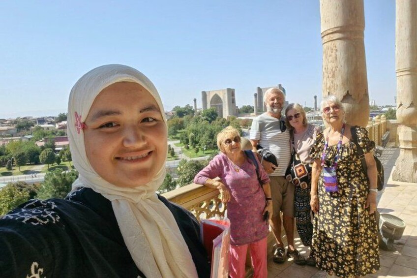 A group of people standing near ancient columns with a cityscape in the background. 2