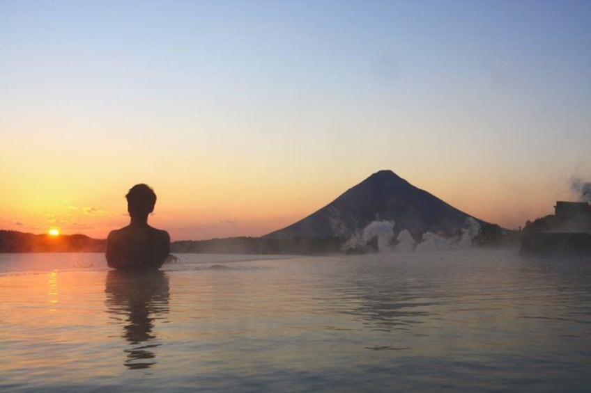 A person in a natural hot spring with a mountain in the background. 1