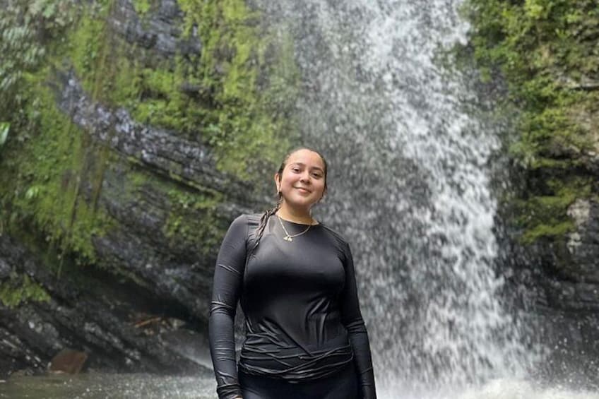 A person standing in front of a waterfall with moss-covered rocks. 2