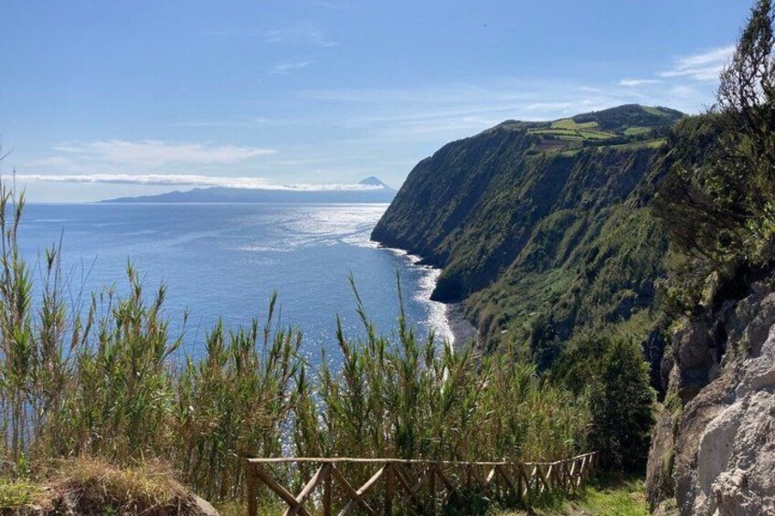 A coastal landscape with a wooden viewing platform, a cliff, and the ocean. 2