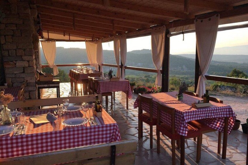 An outdoor dining area with checkered tablecloths, wooden tables, and chairs. 4
