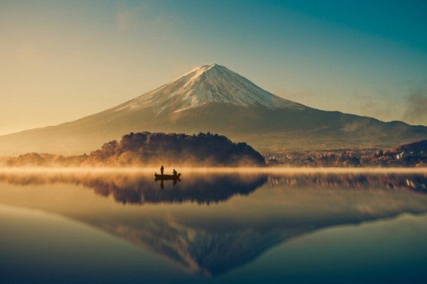 A calm lake with a reflection of a mountain and a small boat. 1