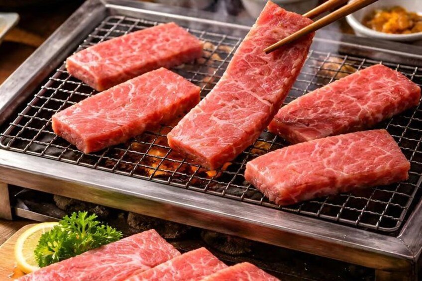 Raw meat on a grill with chopsticks, a lemon, and parsley. 5