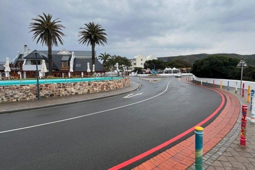 A curved road with a red curb, palm trees, and buildings along the side. 5
