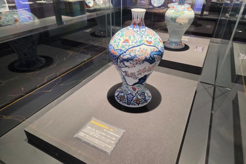 A glass display case containing a blue and white vase with a floral design. 5