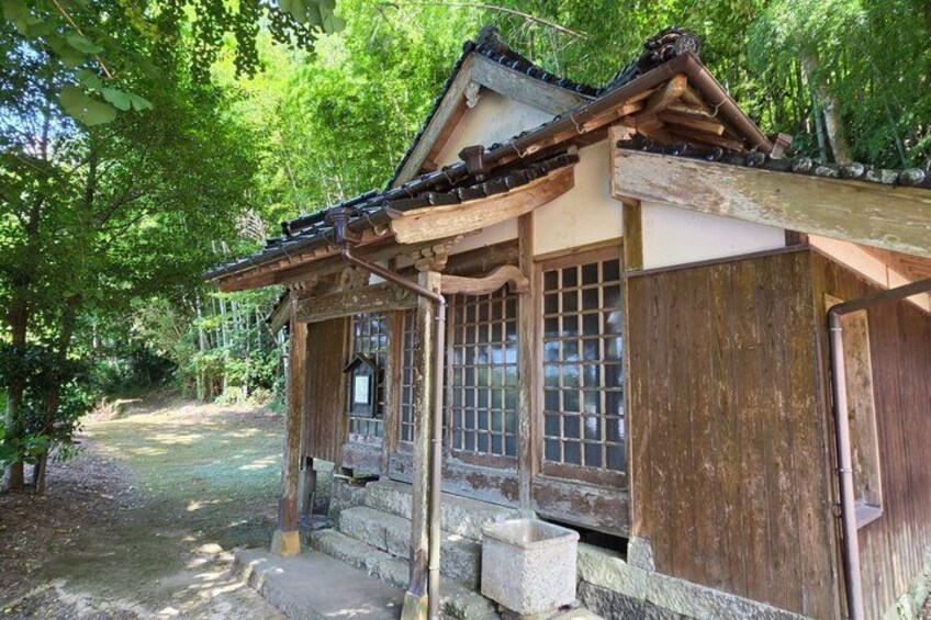 A traditional Japanese building with a tiled roof, wooden structure, and a stone pathway leading to it. 3
