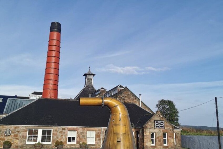 A building with a tall chimney, a large curved pipe, and a stone structure with a chimney. 2