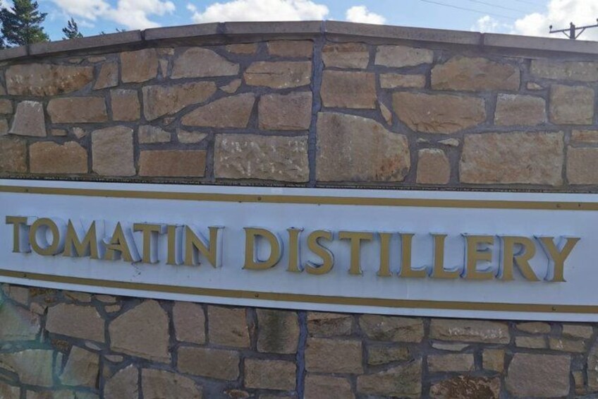 A stone wall with a sign that reads 'TOMATIN DISTILLERY.' 1