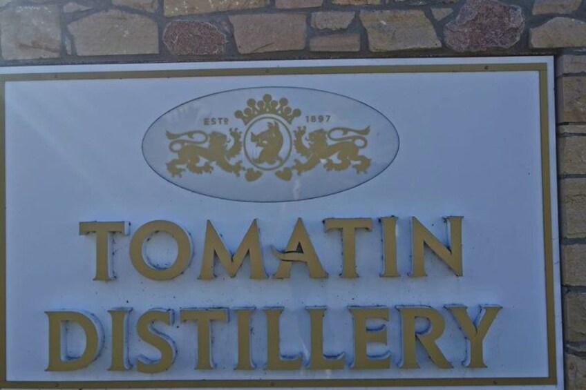 A sign for Tomatin Distillery with a crest and the year 1897. 4