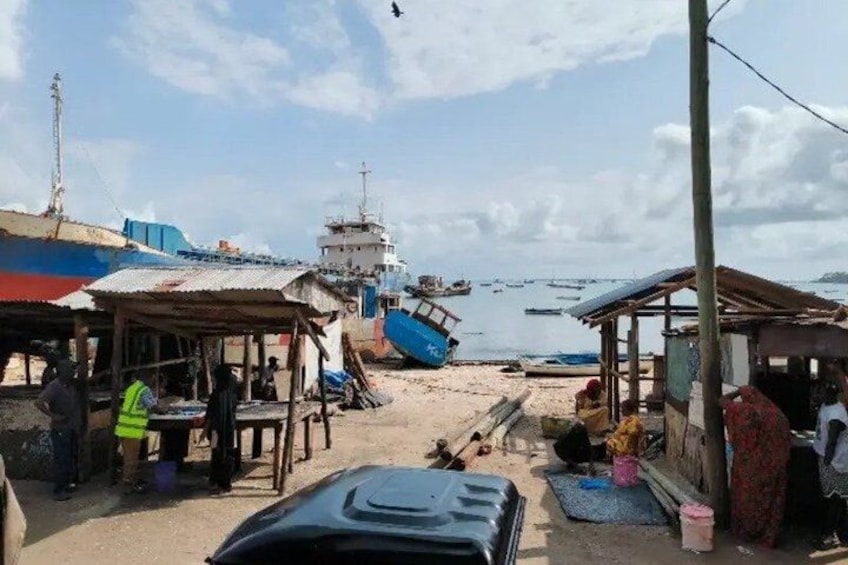 A coastal scene with boats, a pier, and small buildings. 5