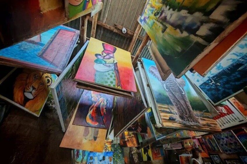 A room filled with various colorful paintings and artworks displayed on walls and hanging from the ceiling. 4
