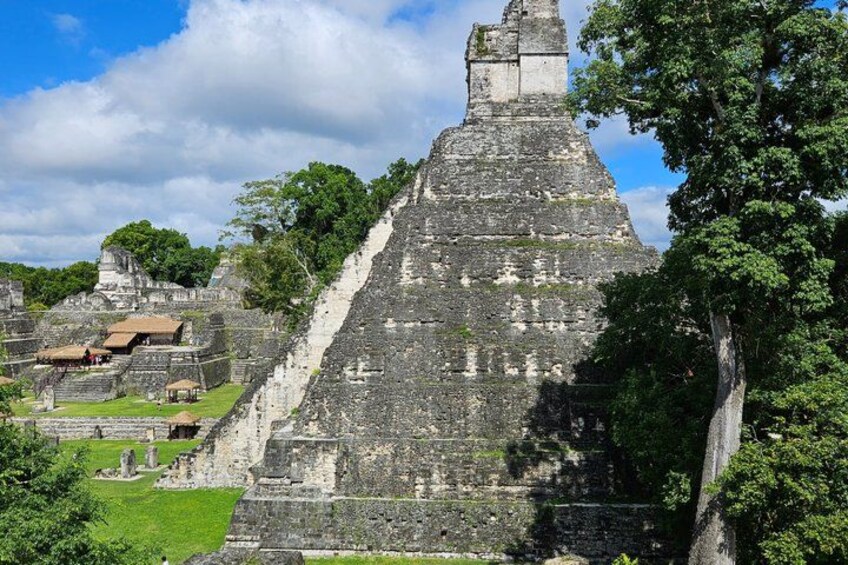 A large ancient pyramid structure surrounded by lush greenery and smaller buildings. 4