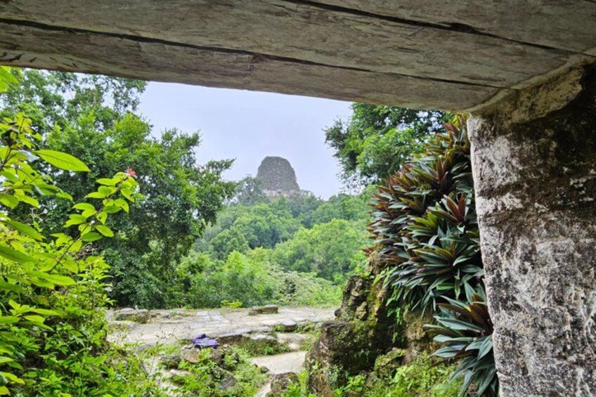 A stone structure with a view of a mountain peak through a forested area. 2