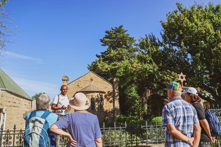 A group of people standing in front of a historic building with a star-shaped roof. 1