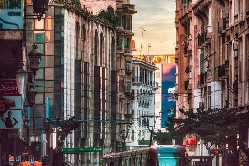 A city street with tall buildings, a tram, and a billboard. 4
