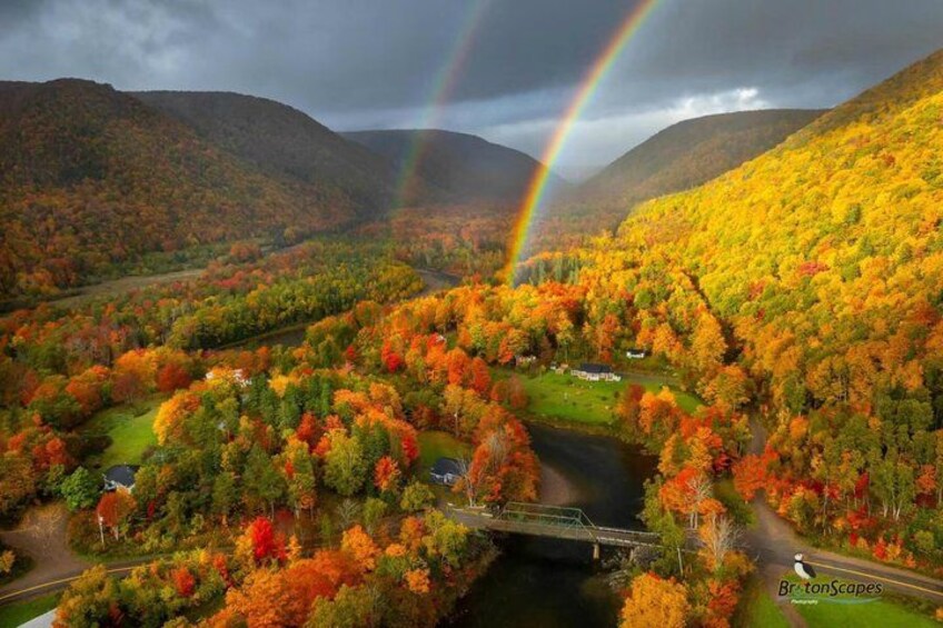 A valley with autumn foliage, a river, a bridge, and a rainbow. 3