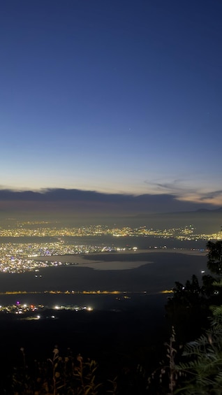 A nighttime cityscape with a river and mountains in the background. 5