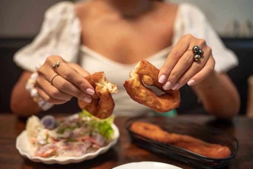 A person holding two fried dough items. 4