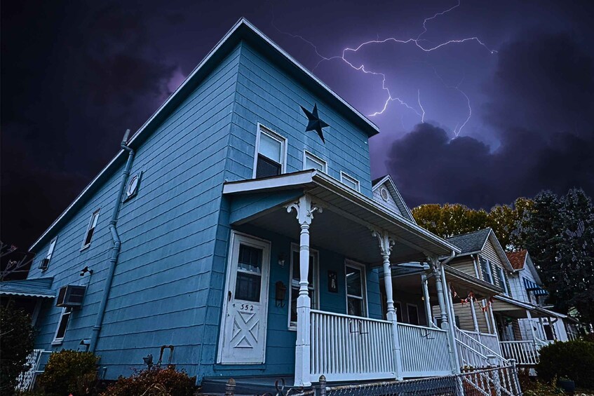 A blue house with a star on the roof, a porch, and a lightning storm in the background. 2