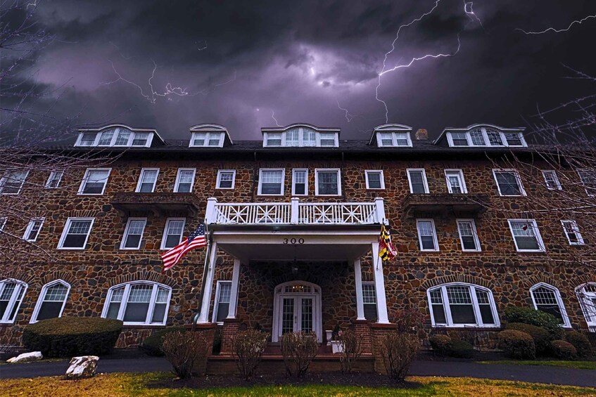 A large stone building with multiple windows and a balcony, under a stormy sky with lightning. 1