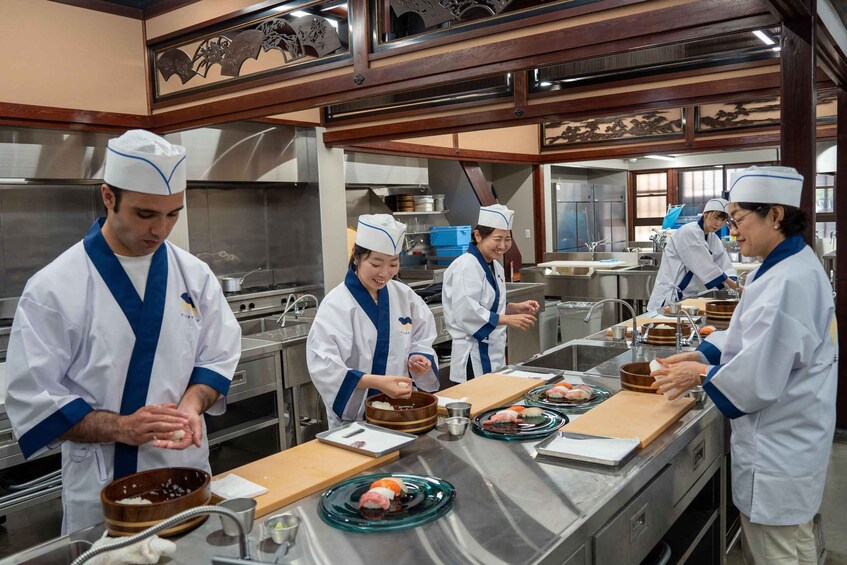 A sushi preparation area with chefs in white uniforms. 2