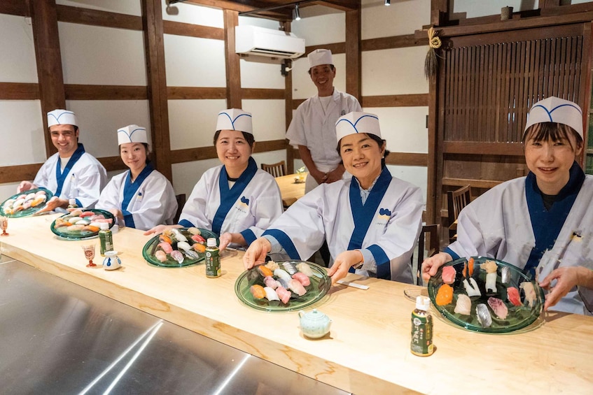 A sushi bar with chefs serving sushi. 1
