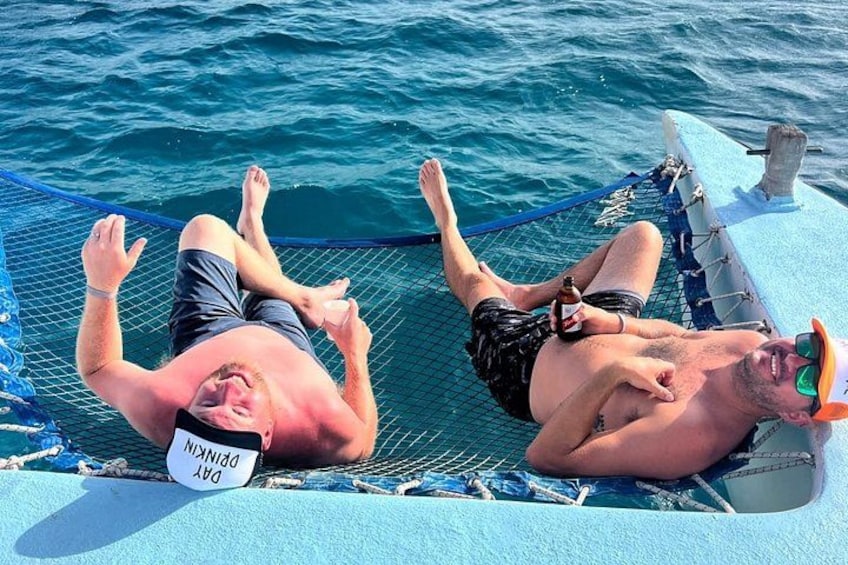Two men lying on a hammock on a boat in the water. 5