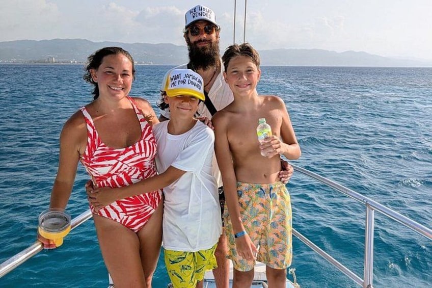A family on a boat with a clear view of the ocean and distant land. 3