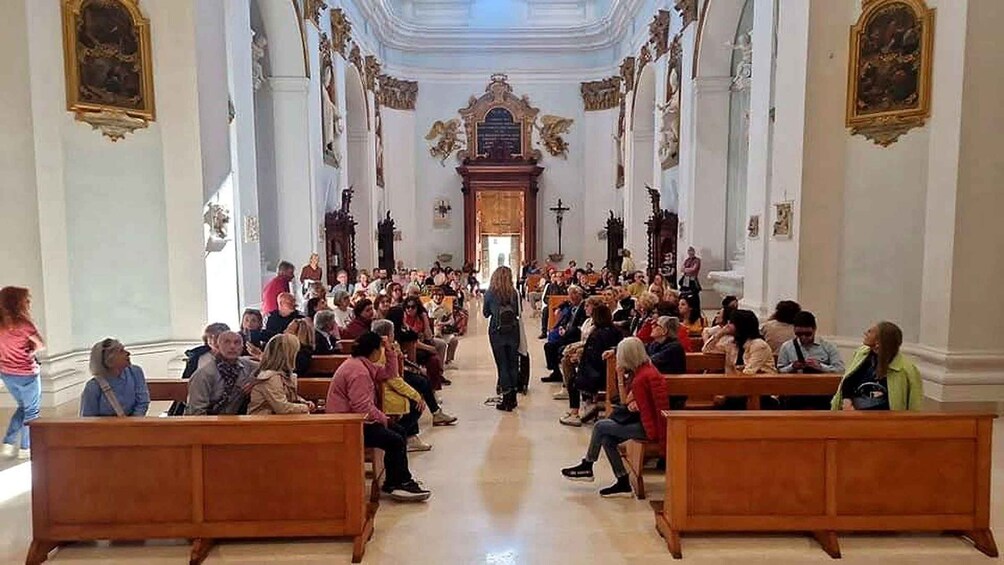 A church interior with pews, a central aisle, and a congregation. 2