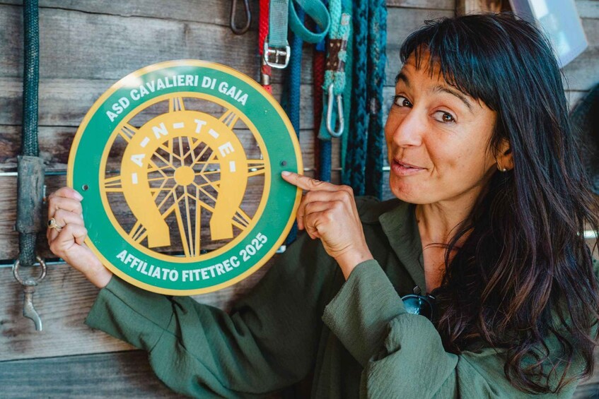 A person holding a circular badge with text and a design. 1