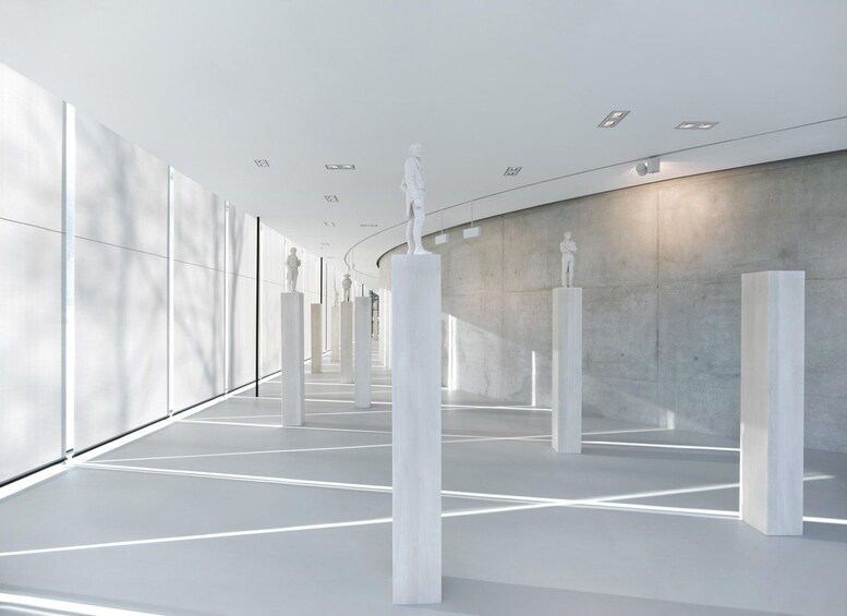 A modern art gallery with white sculptures on pedestals. 3