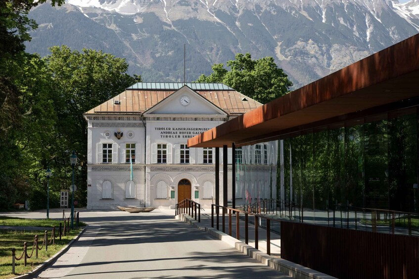 A museum with a mountain backdrop, a large clock, and a pathway leading to the entrance. 4