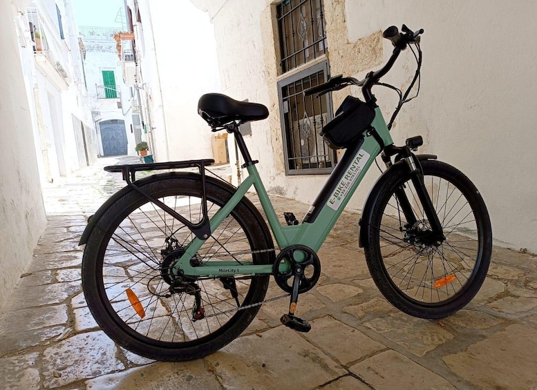 A green electric bike parked on a cobblestone street. 5