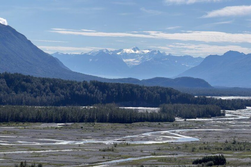 A river winding through a valley with dense forests and snow-capped mountains in the background. 2