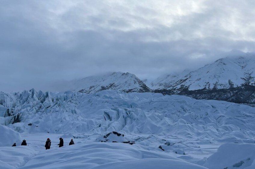 A snowy mountainous landscape with a group of people standing on a snow-covered slope. 5
