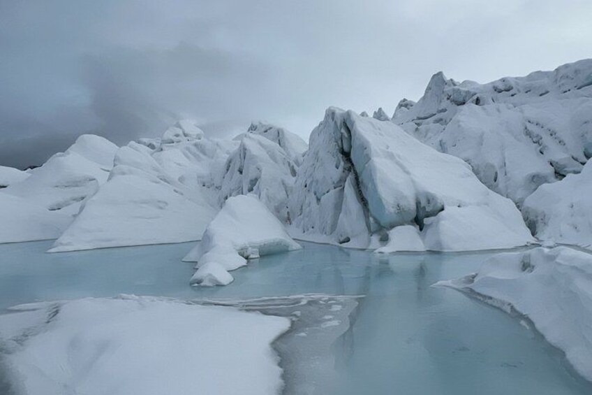 A glacier with icebergs and a partially frozen lake. 1
