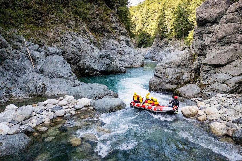 A group of people rafting down a river surrounded by rocky terrain and dense forest. 3