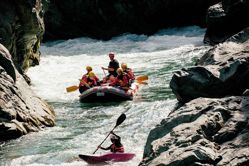 A group of people in a raft navigating a river surrounded by rocky cliffs. 2