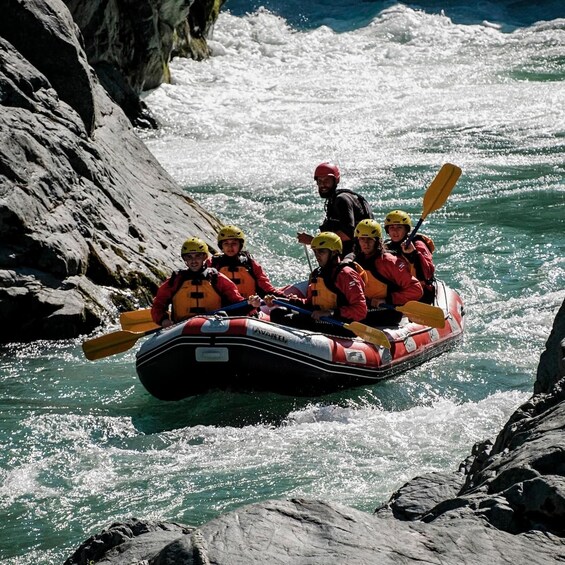 A group of people in a raft navigating a river with rocky banks. 4