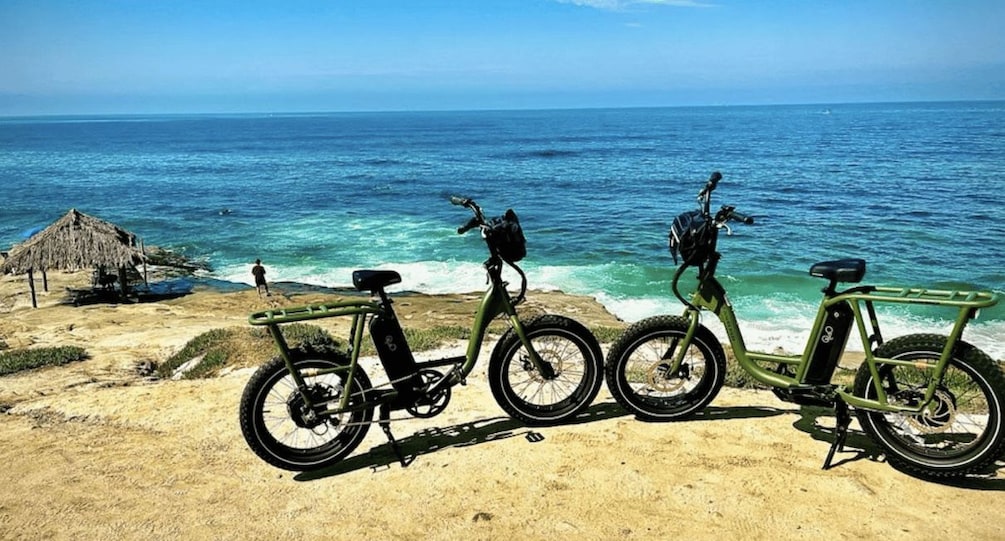 Three bicycles on a sandy beach with the ocean in the background. 1