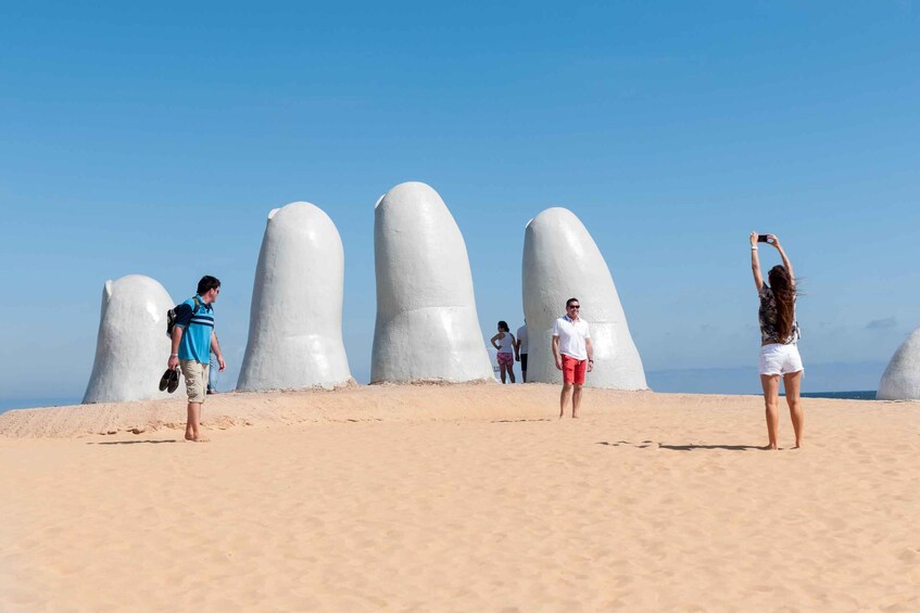 A sandy beach with large white sculptures and people. 3