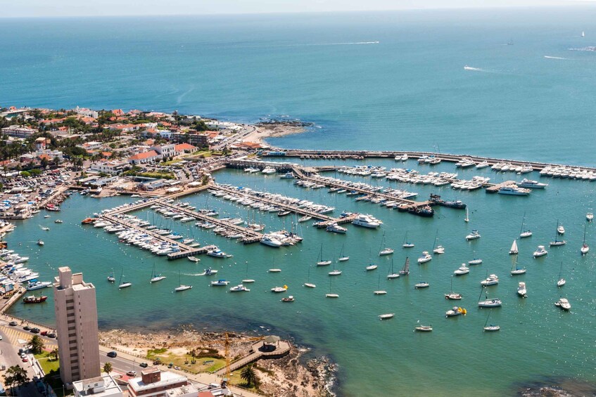 A coastal town with a marina filled with boats, a sandy beach, and buildings along the shore. 2