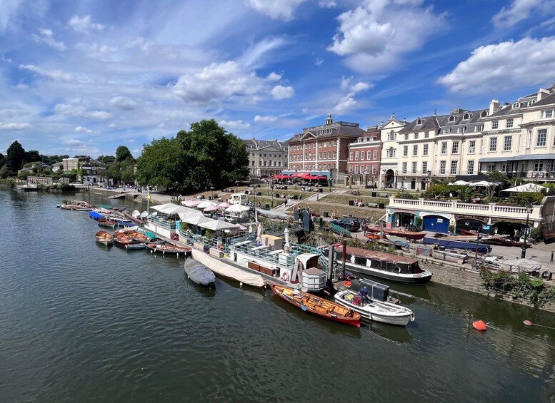 A riverside town with boats docked along the water, buildings, and a clear sky. 1