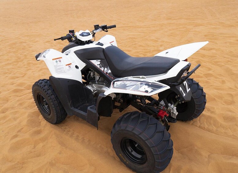 A white and black ATV with large tires on a sandy surface. 4