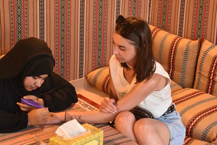 Two people sitting on a patterned sofa, one applying a bandage to the other's arm. 2