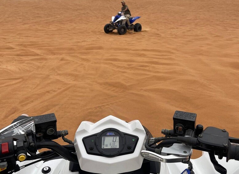 A desert landscape with a person riding a blue quad bike in the distance. 5
