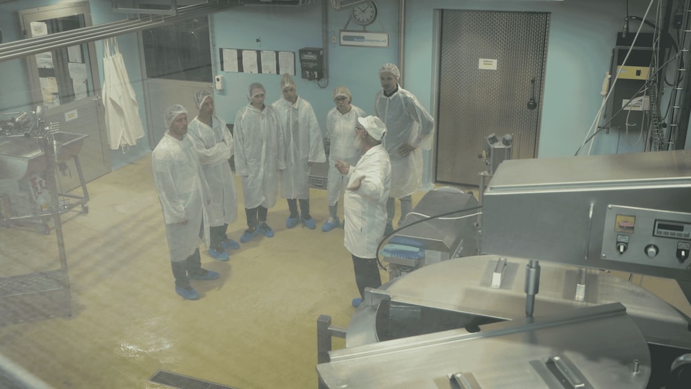 A group of people in a medical facility, some wearing protective gowns and caps, standing in a circle. 3